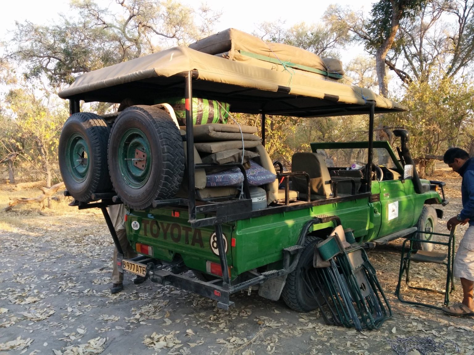 Open safari truck loaded with tents, chairs and camping gear at a bush camp in Botswana