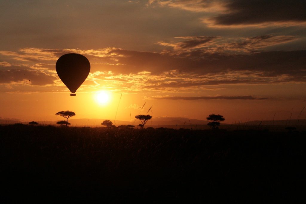 Hot air balloon silhouetted against the rising sun over the Masai Mara