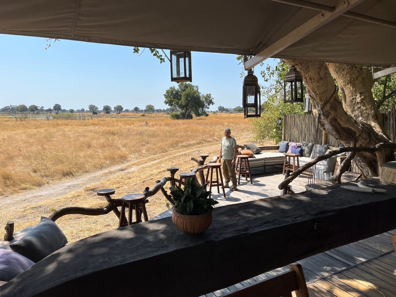 Shaded lounge deck of a safari camp overlooking a golden floodplain in Botswana
