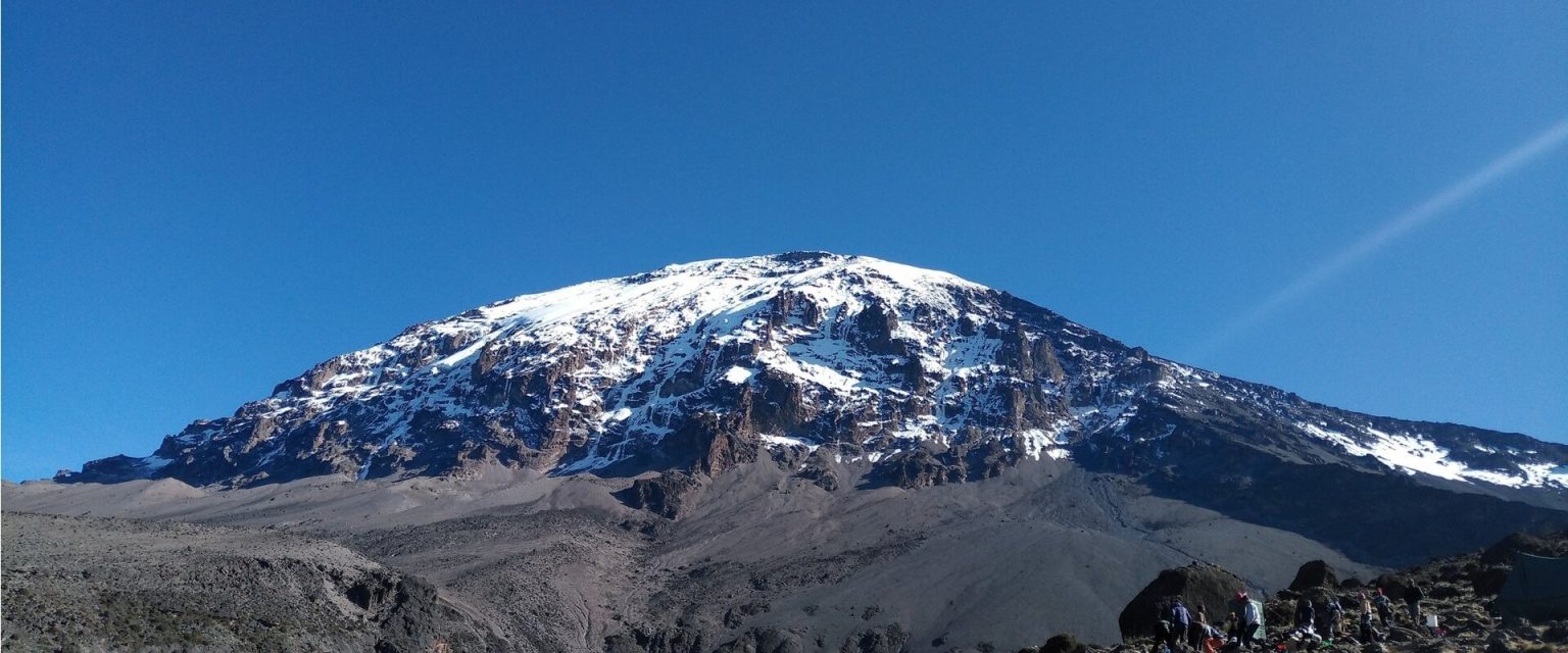 Snow capped Kibo dome rising above the alpine desert of Kilimanjaro under a clear sky
