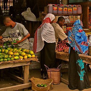 Stall holders and shoppers in headscarves at a fruit and vegetable market in Stone Town, Zanzibar