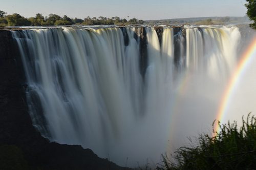 Victoria Falls curtain with a rainbow in the spray in late afternoon light