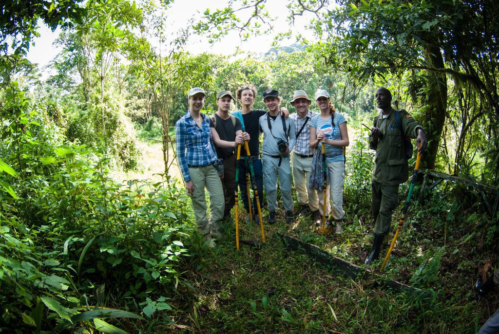 Trekkers in long trousers, gaiters and gloves with a ranger in the forest before a gorilla trek