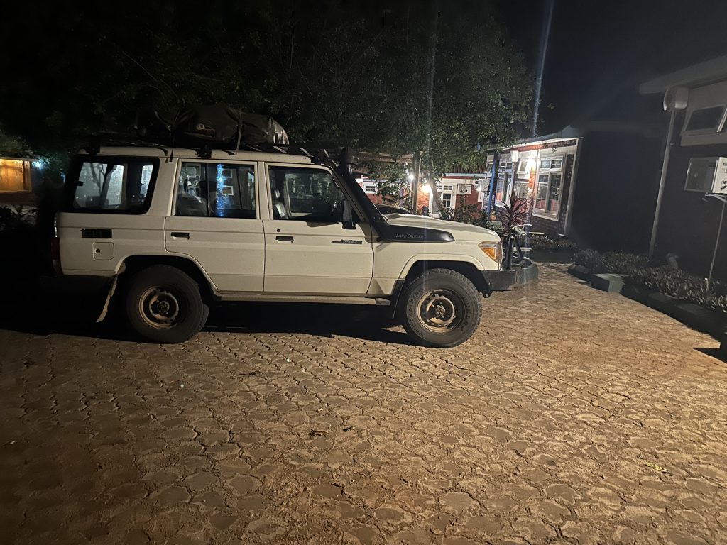 White Land Cruiser parked outside a lodge at night