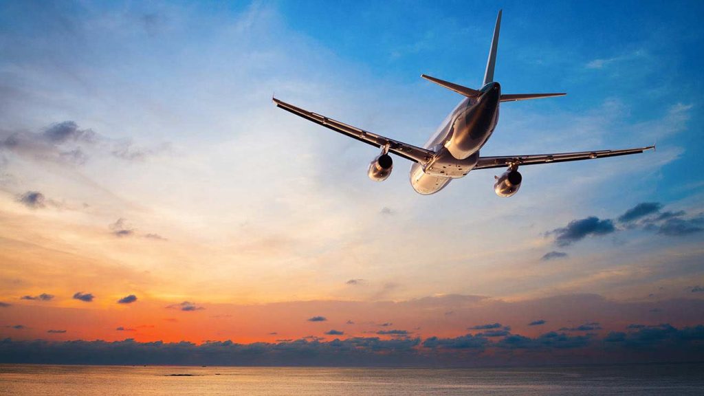 Twin engine airliner climbing away at sunset over the sea