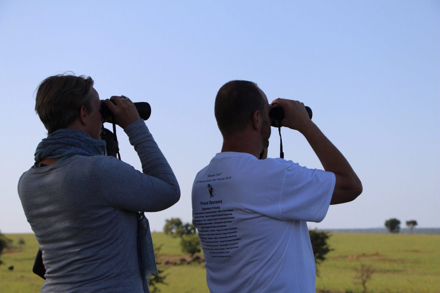 Two visitors scanning the savanna with binoculars in Kidepo Valley National Park